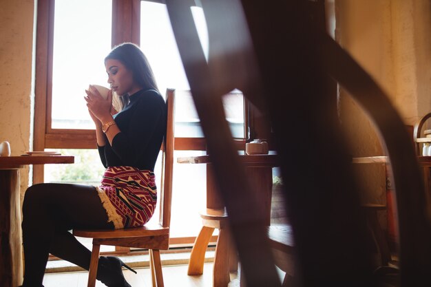 Donna che mangia una tazza di caffè in caffè