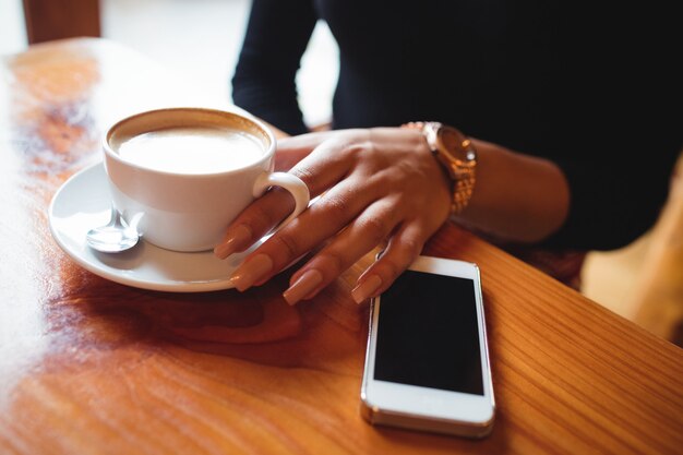 Donna che mangia una tazza di caffè in caffè