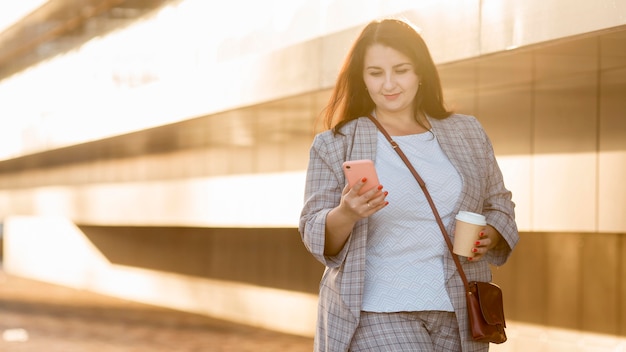 Donna che mantiene il suo telefono all'aperto con copia spazio