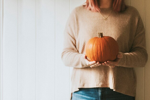 Donna che mantiene la zucca di Halloween in un umore autunnale della fattoria