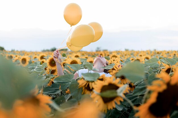 Donna che mantiene palloncini nel campo di girasoli