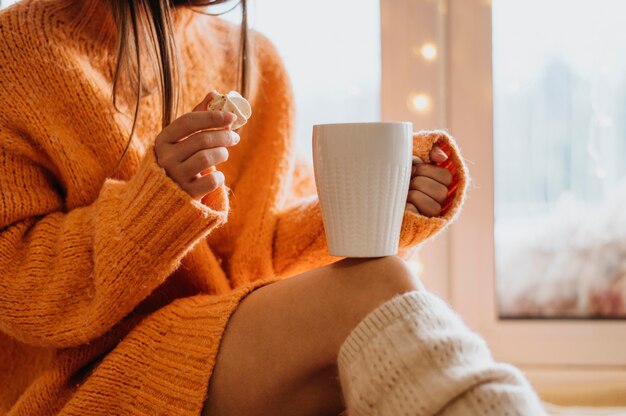 Donna che mantiene una tazza di tè al chiuso