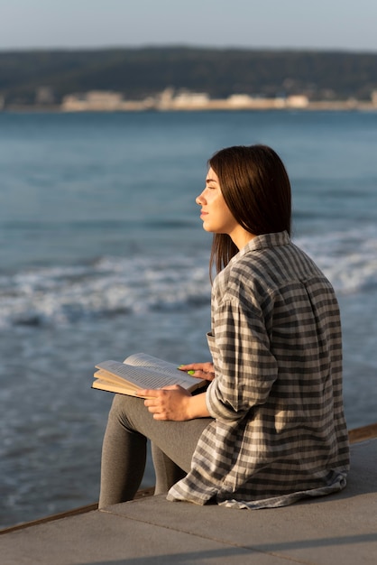 Donna che medita e legge sulla spiaggia