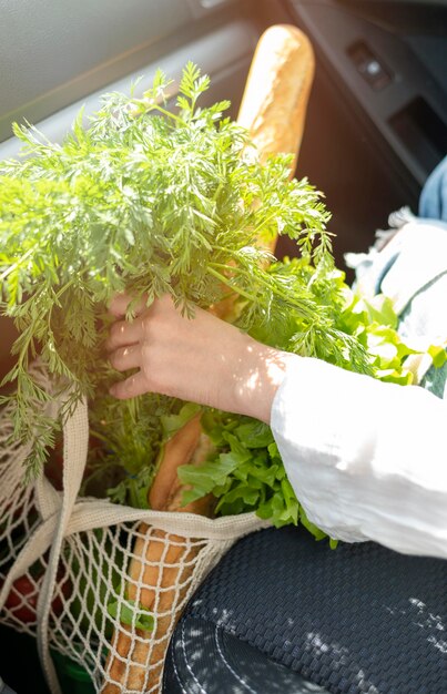 Donna che mette borsa con la spesa in automobile