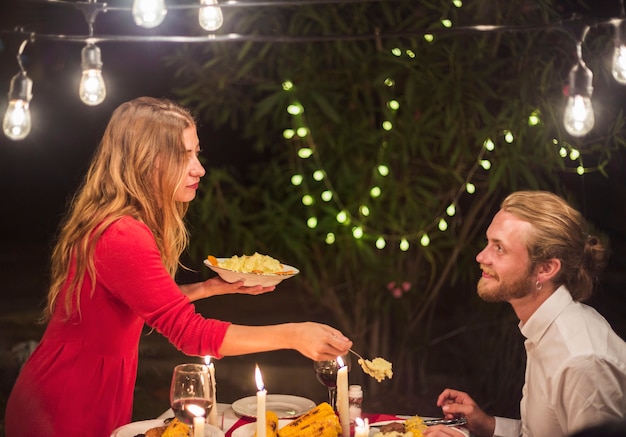 Donna che mette cibo sul piatto dell&#39;uomo