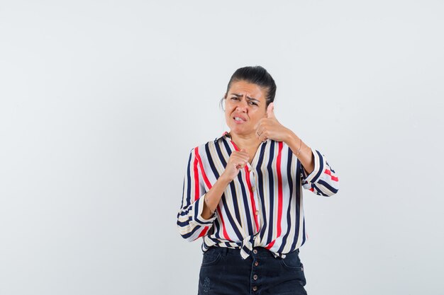 donna che mostra i doppi pollici in su in camicia, gonna e che sembra sicura.