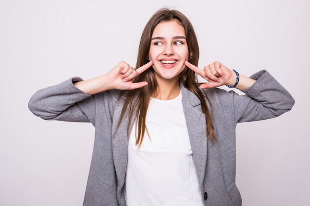 Donna che mostra i suoi denti bianchi diritti perfetti su fondo bianco