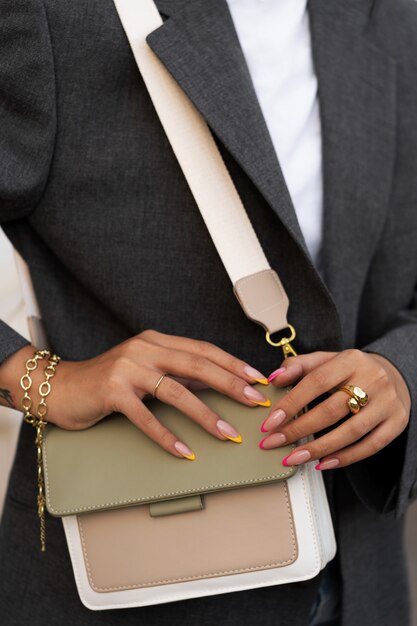 Donna che mostra la sua nail art sulle unghie con la borsa