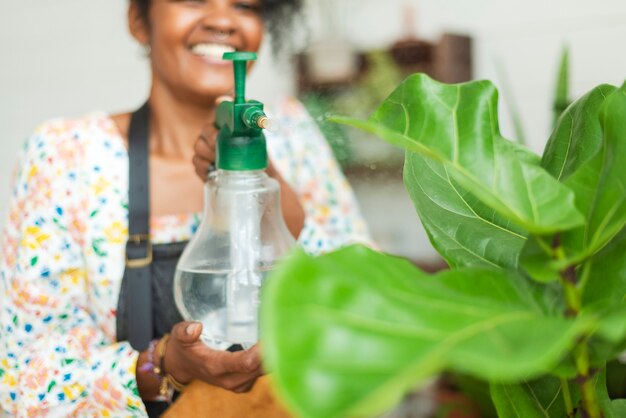 Donna che nebulizza le piante con uno spruzzo d'acqua in un negozio di piante