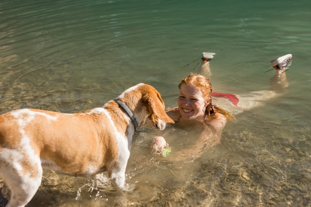 Donna che nuota e gioca con la vista lunga del cane