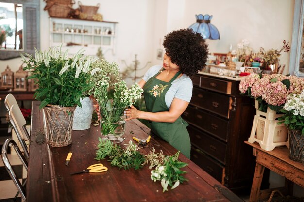 Donna che organizza i fiori sulla tavola di legno