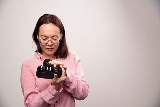 Donna che osserva su una macchina fotografica su un bianco. Foto di alta qualità