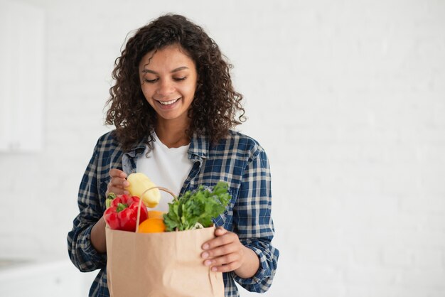 Donna che osserva sulle verdure da una borsa