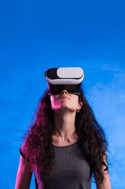 Donna che per mezzo della cuffia avricolare di realtà virtuale all'aperto