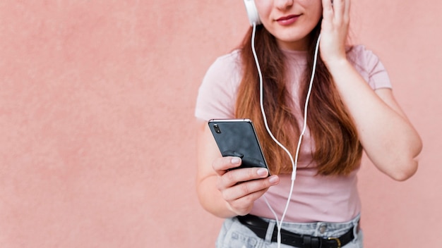 Donna che per mezzo dello smartphone e delle cuffie per ascoltare musica