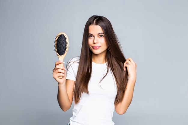 Donna che pettina i suoi capelli isolati su un bianco