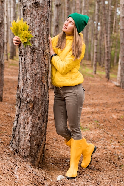 Donna che posa accanto ad un albero mentre distogliendo lo sguardo
