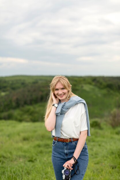 Donna che posa mentre tenendo macchina fotografica in natura