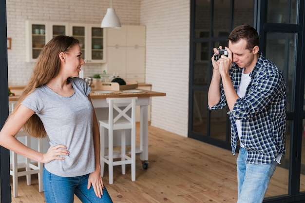 Donna che posa per il colpo mentre uomo che usando la macchina fotografica