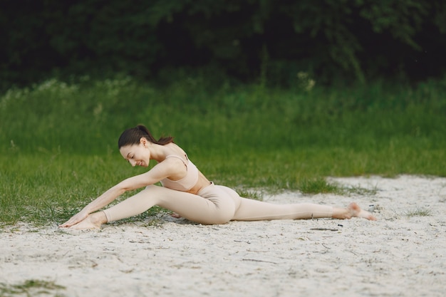 Donna che pratica yoga avanzata in una spiaggia