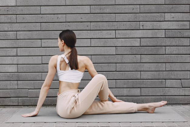 Donna che pratica yoga avanzato contro un muro urbano scuro