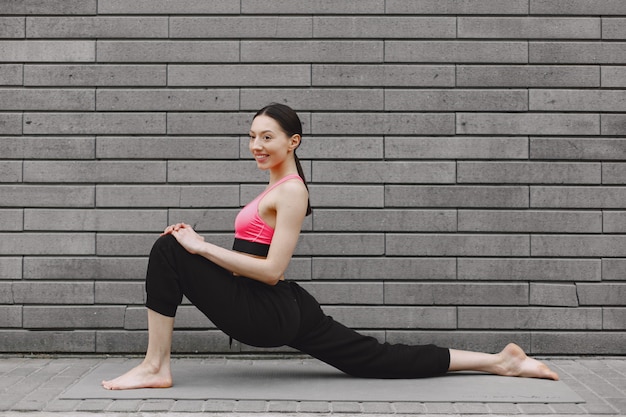Donna che pratica yoga avanzato contro un muro urbano scuro