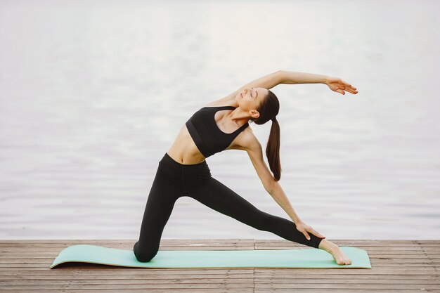 Donna che pratica yoga avanzato dall'acqua