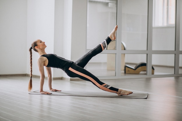 Donna che pratica yoga in palestra su una stuoia