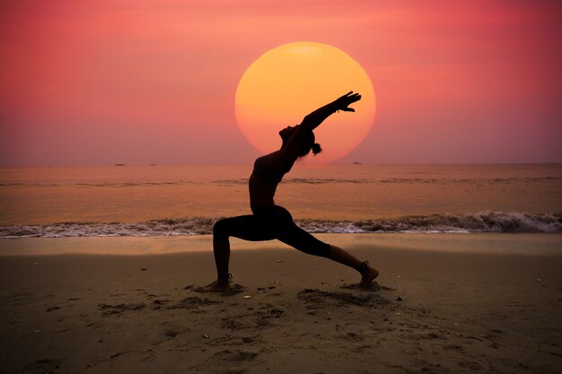 Donna che praticano yoga con il sole dietro di lei