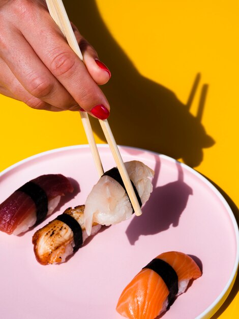 Donna che prende un sushi da un piatto con i sushi