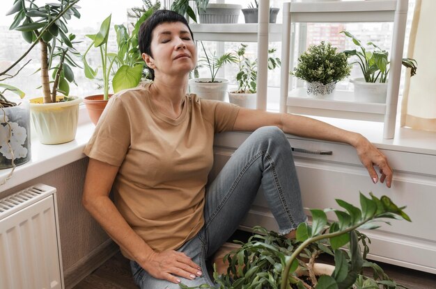 Donna che prende una pausa dalla cura delle piante d'appartamento