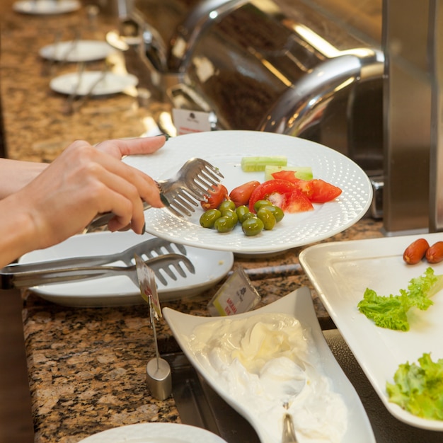 Donna che prepara insalata in una cucina. vista laterale.