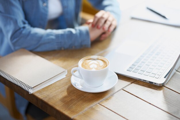 Donna che prepara per lavorare nella caffetteria con il computer portatile