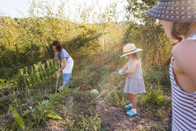 Donna che raccoglie verdure con le sue due figlie nella fattoria