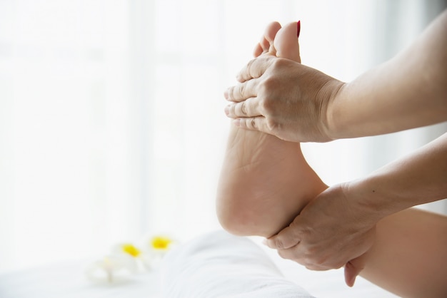 Donna che riceve il servizio di massaggio ai piedi da massaggiatrice vicino a portata di mano e piedi - rilassarsi nel concetto di servizio di massaggio di massaggio del piede