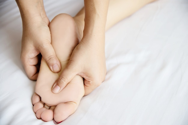 Donna che riceve il servizio di massaggio ai piedi da massaggiatrice vicino a portata di mano e piedi - rilassarsi nel concetto di servizio di massaggio di massaggio del piede