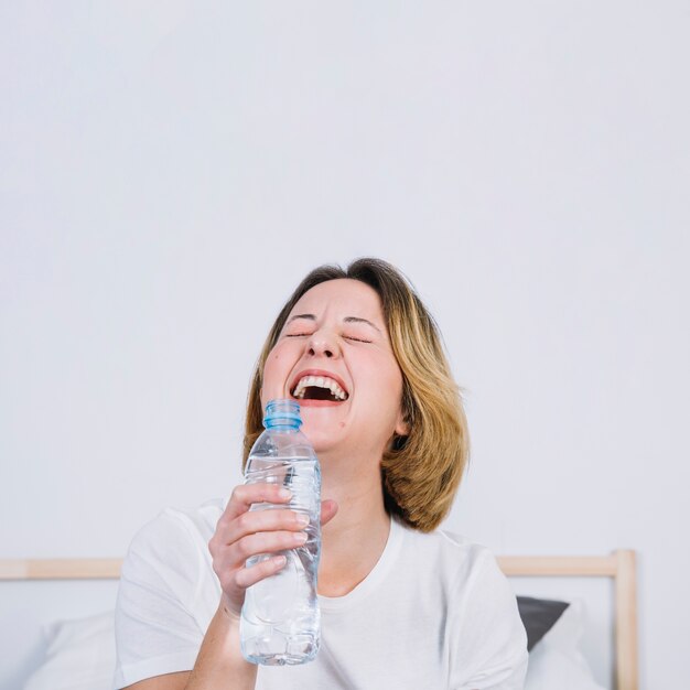 Donna che ride con una bottiglia d&#39;acqua