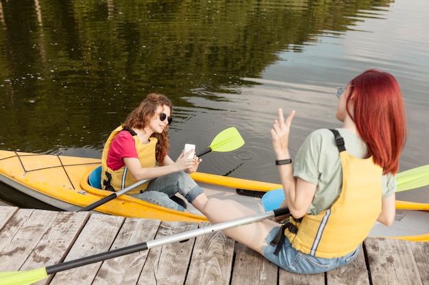 Donna che rimane in kayak e scatta foto di un amico