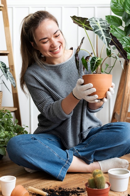 Donna che rinvasa una pianta d'appartamento all'interno della sua casa