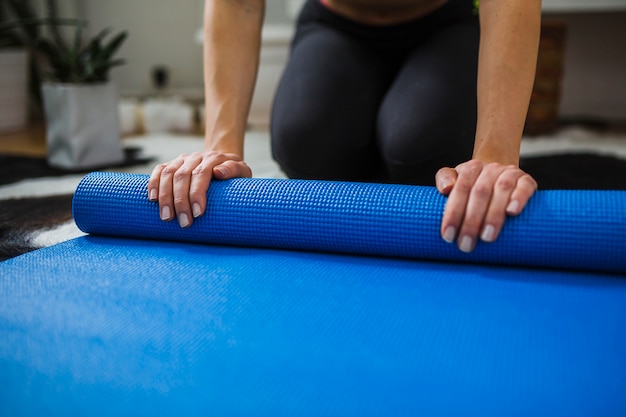 Donna che rotola sulla stuoia blu di yoga