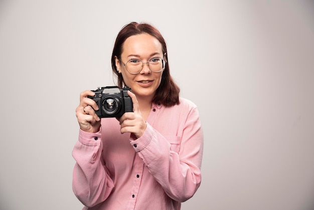 Donna che scatta una foto con la fotocamera su bianco. Foto di alta qualità