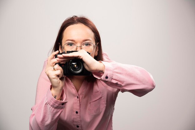 Donna che scatta una foto con la fotocamera su bianco. Foto di alta qualità