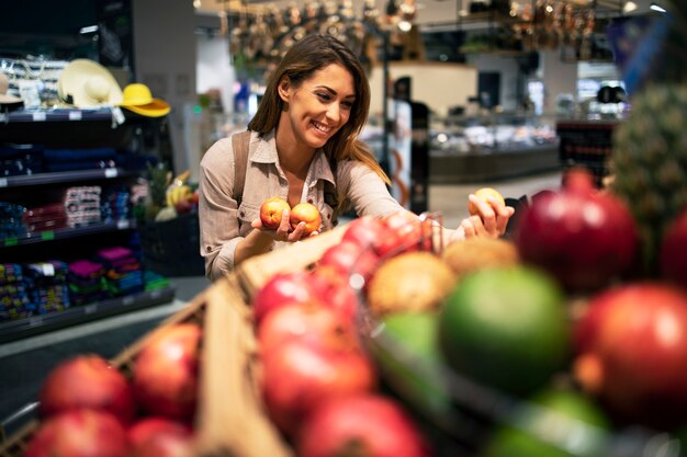 Donna che sceglie con cura la frutta per la sua insalata al supermercato