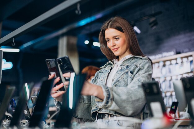 Donna che sceglie il telefono al negozio di tecnologia