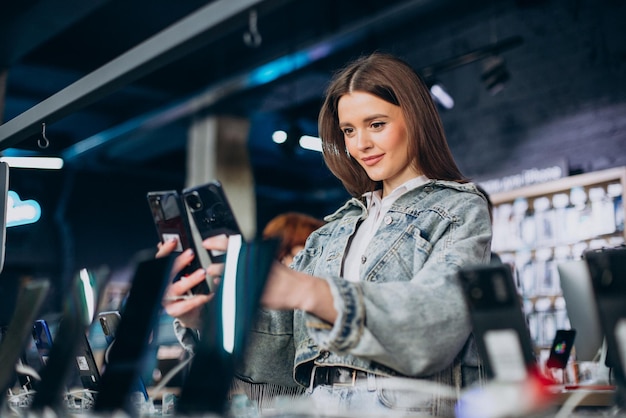 Donna che sceglie il telefono al negozio di tecnologia