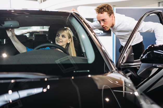 Donna che sceglie un'automobile in una sala d'esposizione dell'automobile