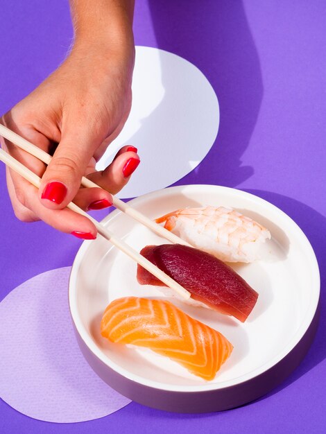 Donna che seleziona un sushi di tonno con le bacchette dal piatto