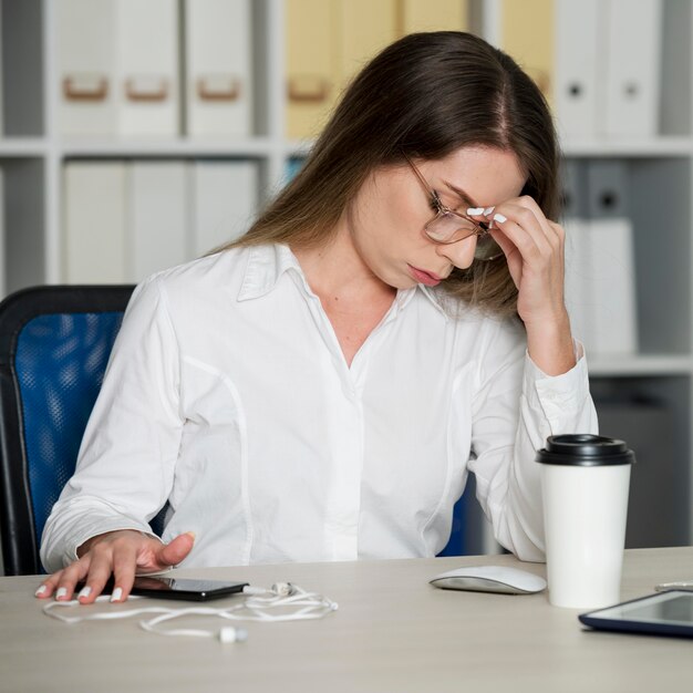 Donna che sembra stanca al lavoro a causa del tempo trascorso al telefono