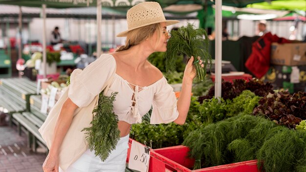 Donna che sente l'odore di un po 'di aneto dal mercato