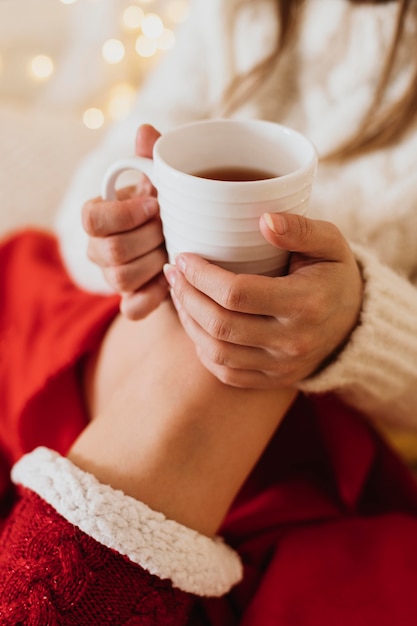 Donna che si distende a casa e che tiene una tazza di tè